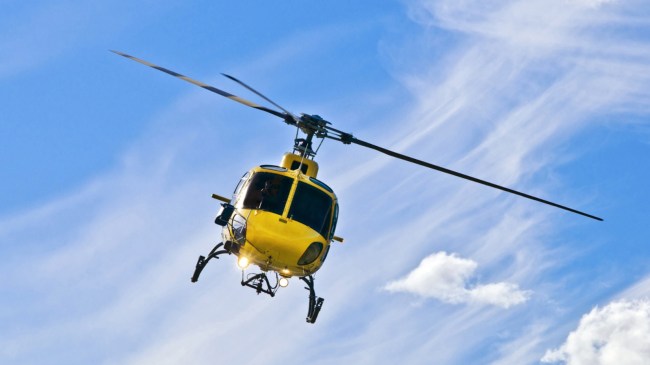 A yellow helicopter flies through the air.