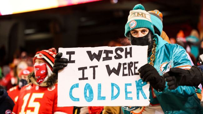 a dolphins fan holding a sign at a chiefs game