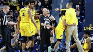 Juwan Howard gets held back by a Michigan player on the court.