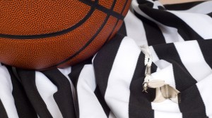 A basketball referee's whistle and uniform lie on the court.