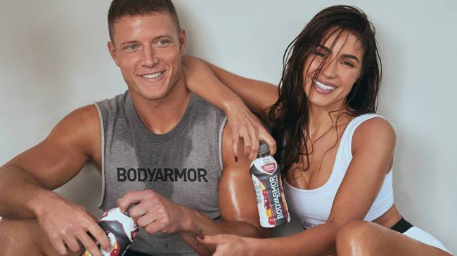 Christian McCaffery and fiancée Olivia Culpo holding BODYARMOR sports drink bottles