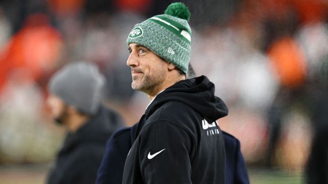 aaron rodgers smirking while wearing a green jets beanie