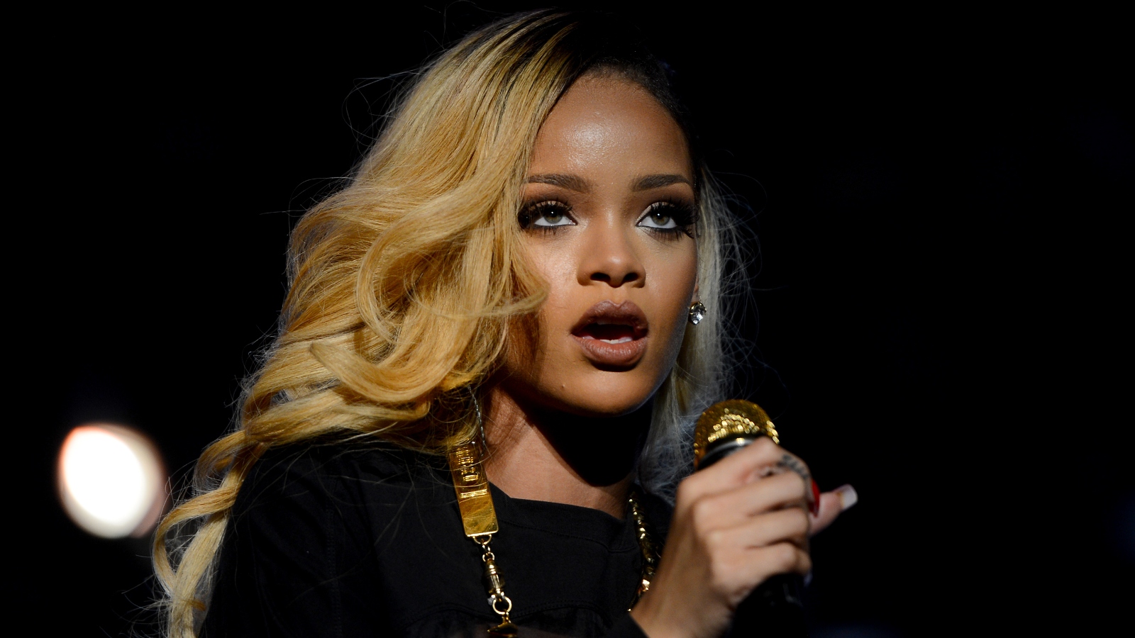 Rihanna performing with a golden microphone