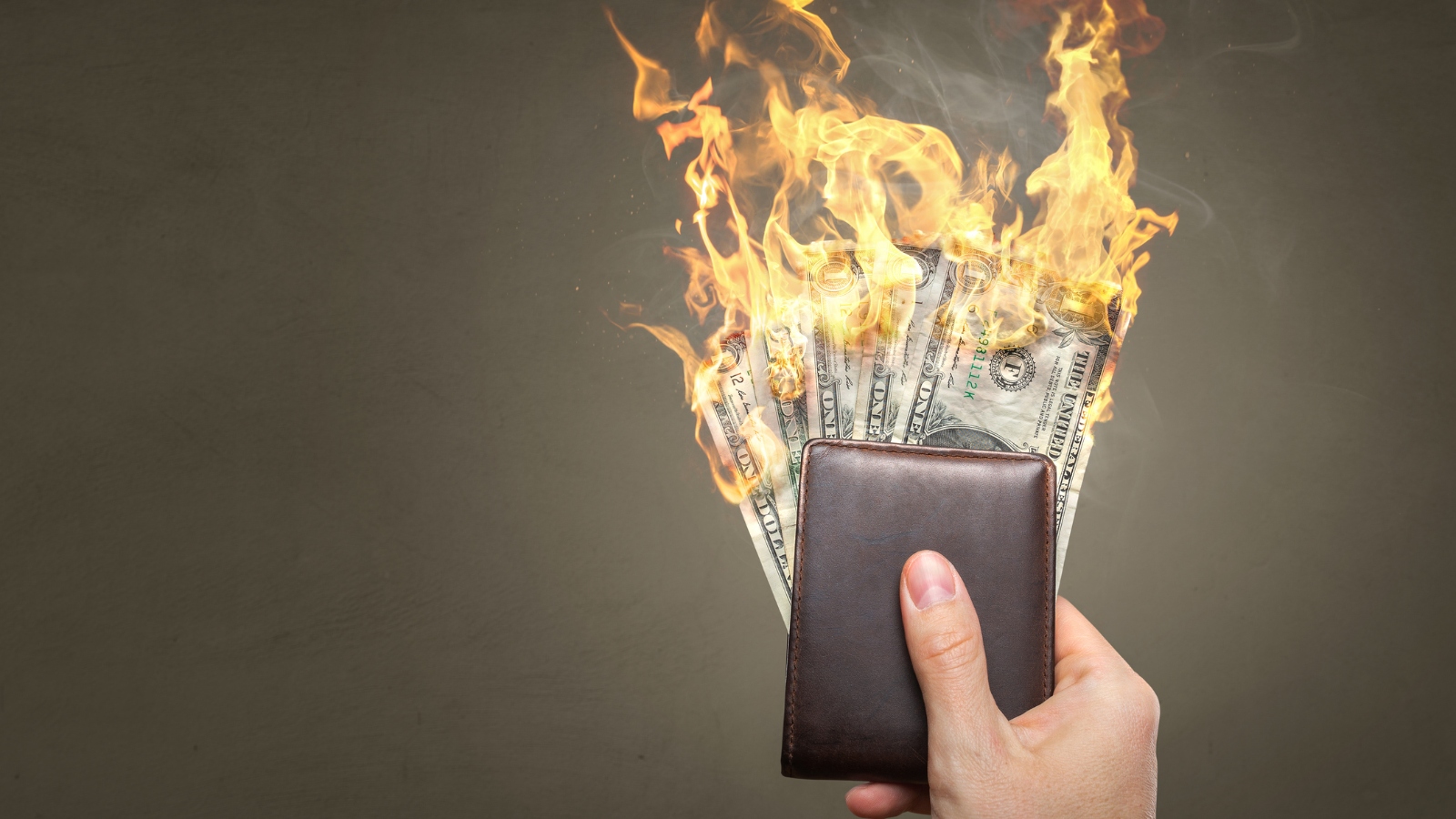 man holding a wallet with money on fire