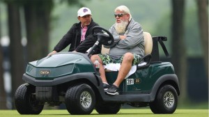 John Daly drives a golf cart during practice round prior to 2024 PGA Championship