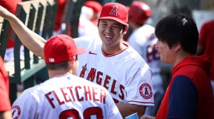 Shohei Ohtani talks with David Fletcher and interpreter Ippei Muzuhara in the dugout during game