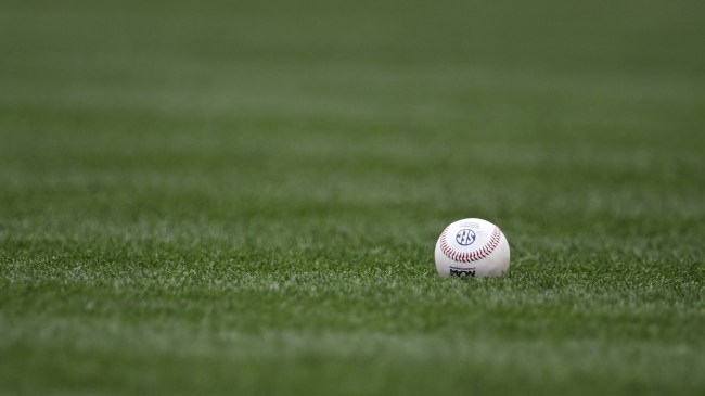 A baseball with an SEC logo lies in the outfield grass.