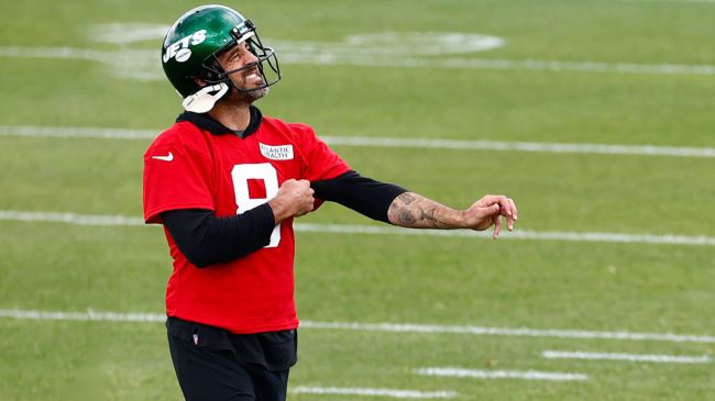 aaron rodgers in a red shirt and jets helmet