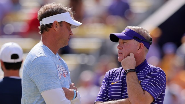 Lane Kiffin and Brian Kelly meet on the field before a game between LSU and Ole Miss.