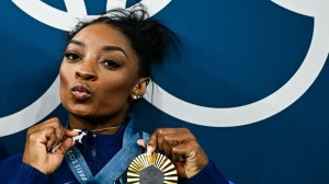 US' Simone Biles poses with her gold medal and a goat necklace after the podium ceremony for the artistic gymnastics women's all around final of the Paris 2024 Olympic Games at the Bercy Arena in Paris, on August 1, 2024. (Photo by Loic VENANCE / AFP)