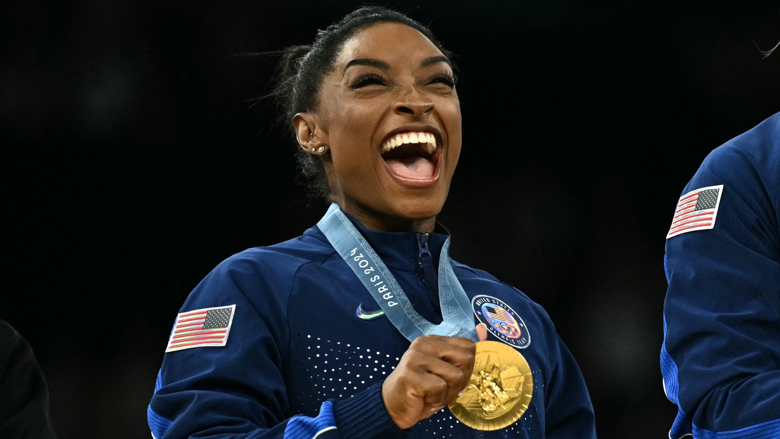 Simone Biles smiling with a gold medal