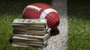 A stack of money next to a football.