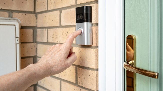 man pressing door bell button with camera