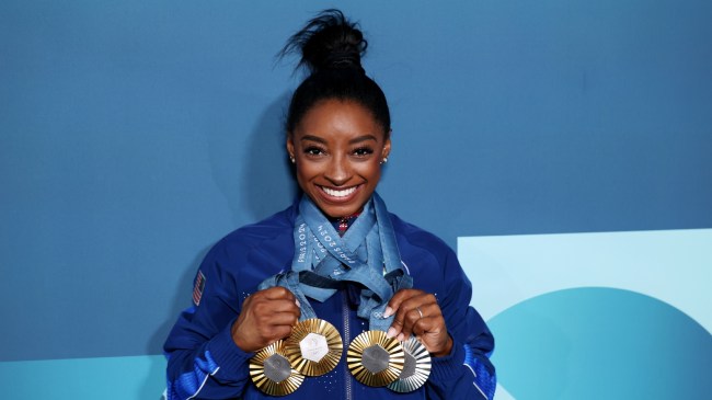 Simone Biles holds up her medals from the Paris Olympics.