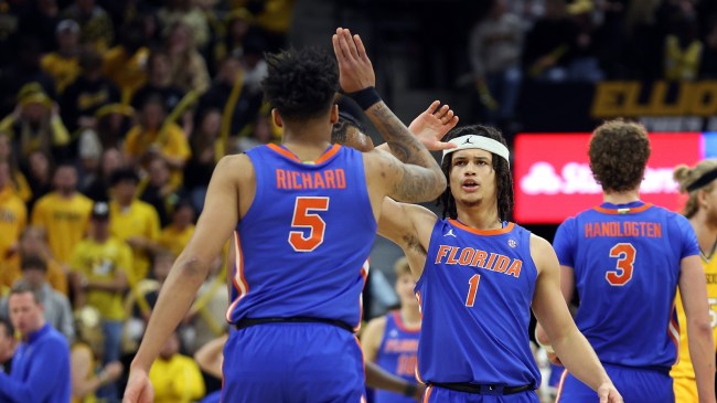 A pair of Florida Gators basketball players high five on the floor.