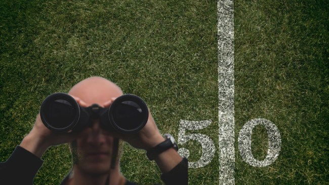 Man with binoculars over background of a football field.