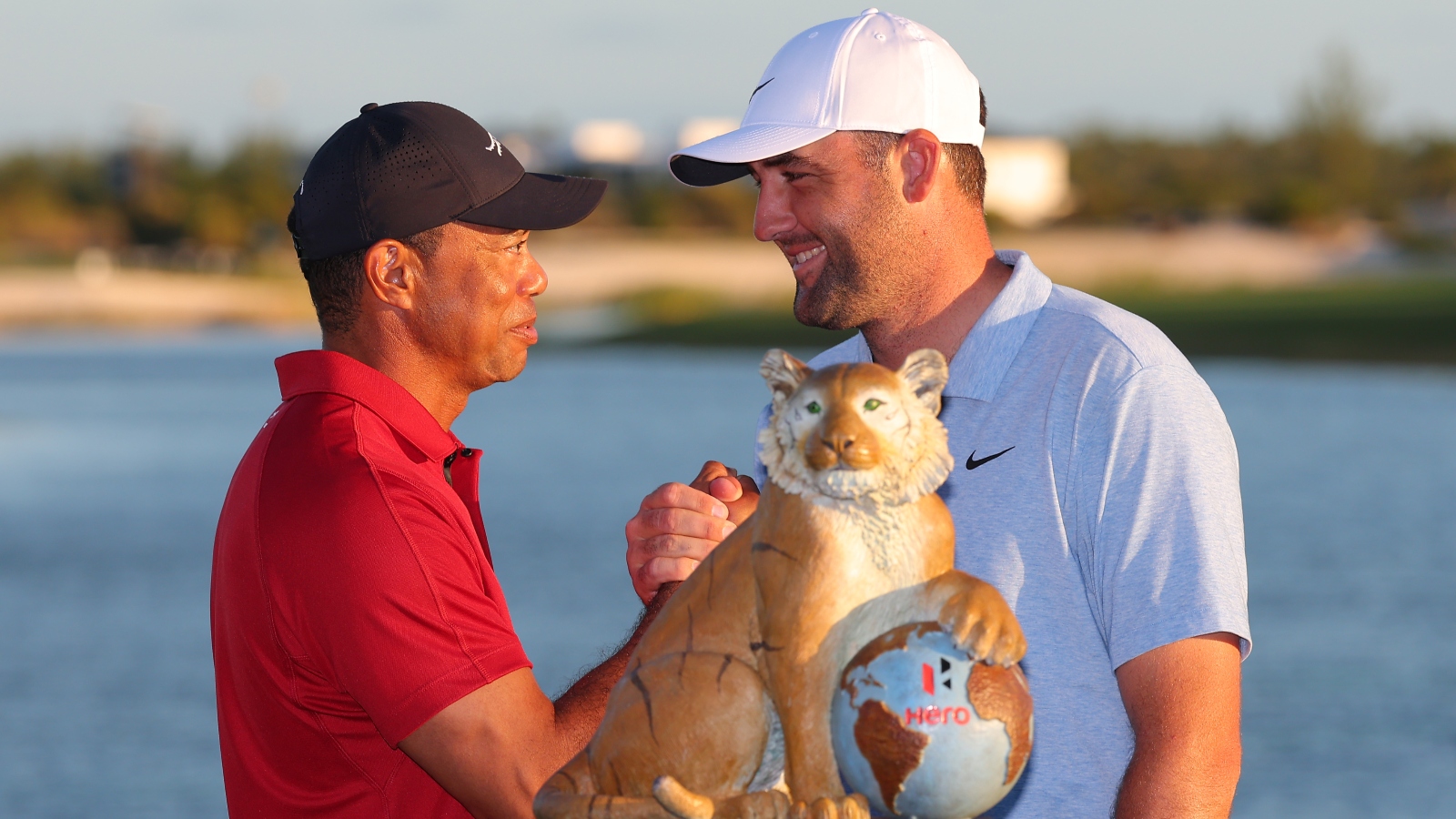 Tiger Woods and Scottie Scheffler shaking hands over a trophy