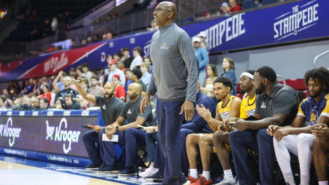 The UNCG Spartans coaching staff on the bench during a basketball game.