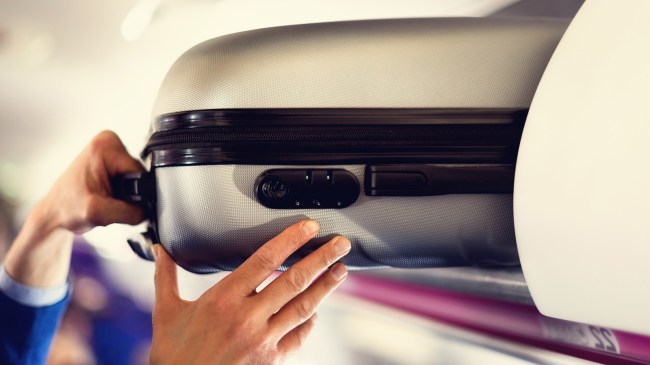 airplane passenger removing suitcase from luggage compartment