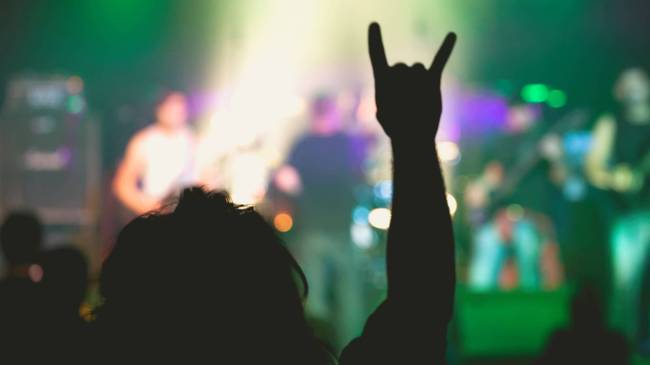 Metal fan throwing up devil horns at concert