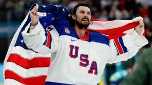Team USA goaltender Connor Hellebuyck with American flag at Winter Olympics