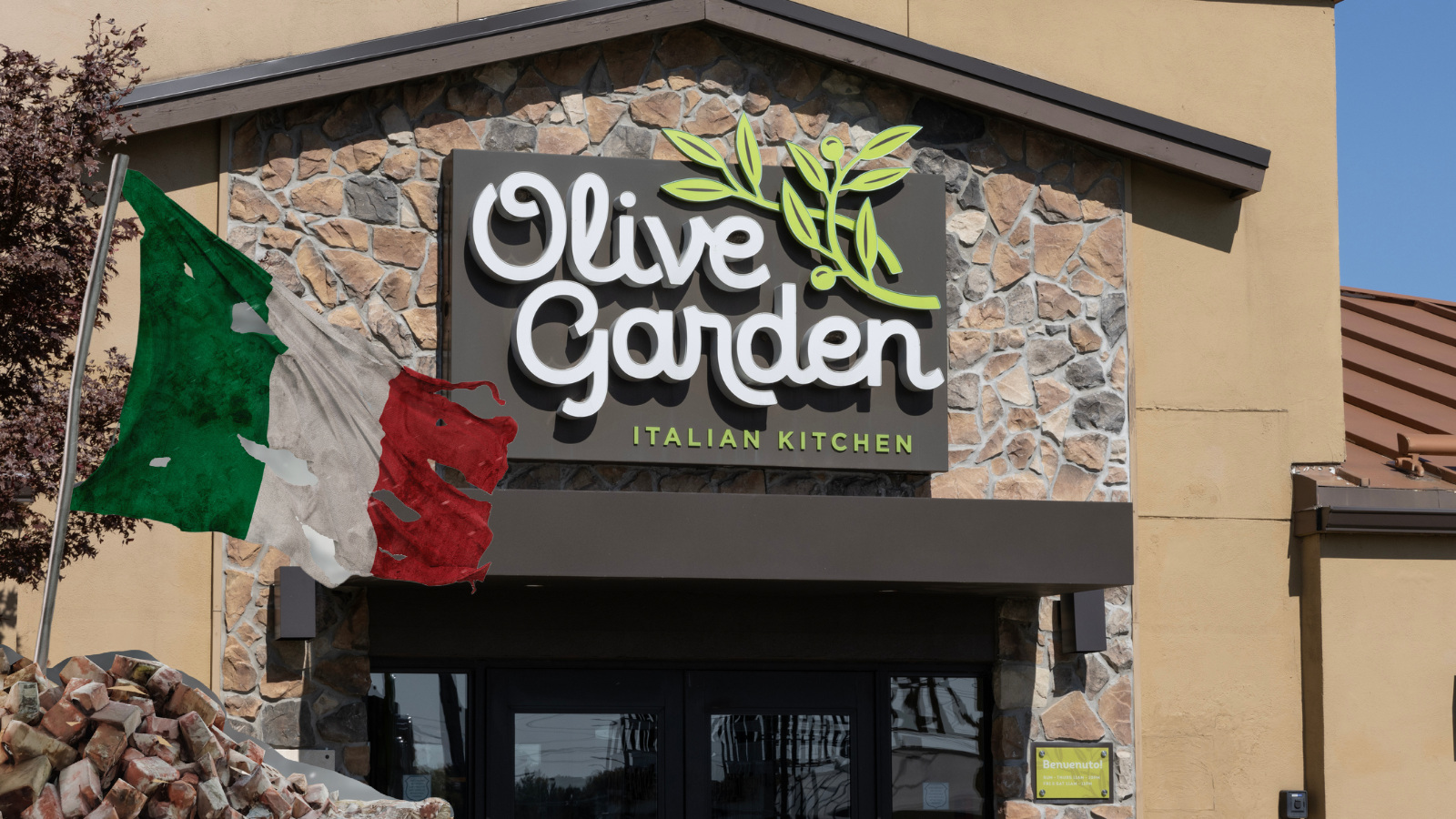Olive garden restaurant with a sad Italian flag in front