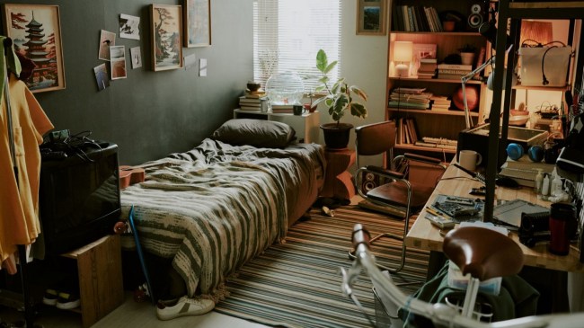 Male dorm room made in pastel colors and decorated with posters, fully equipped with gadgets and personal items.