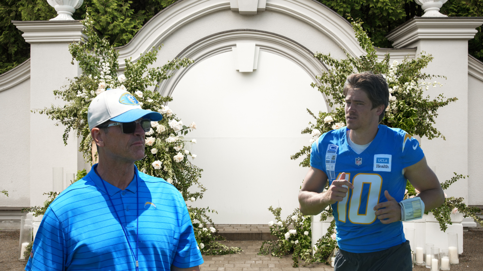 Los Angeles Chargers Head Coach Jim Harbaugh and quarterback Justin Herbert in front of a wedding display