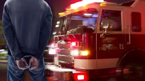 Man in handcuffs next to a fire truck