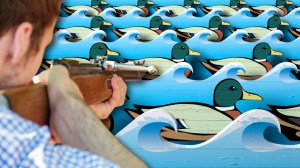 Man with rifle aiming at ducks at carnival shooting gallery