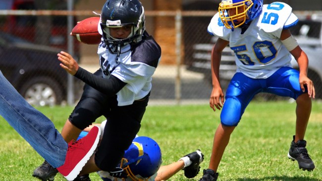 Man tripping youth football player with his leg