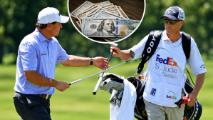 Jun 9, 2017; Memphis, TN, USA; Phil Mickelson and his caddie Jim MacKay during the second round of the FedEx St. Jude Classic golf tournament at TPC Southwind. A stock image of U.S. currency sits between the two.