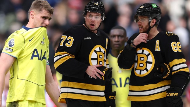 Tottenham Hotspur player next to Bruins players Charlie McAvoy and David Pastrnak