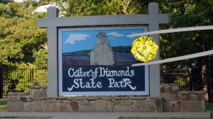 6 carat yellow diamond in front of Crater of Diamonds State Park sign in Arkansas