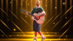Justin Bieber playing guitar on stage with an awards show background